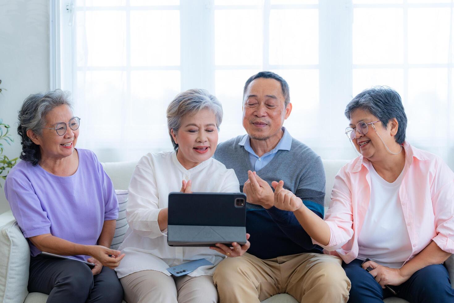 Happiness of the group females and male elderly talking with Call from smart tablet. Senior people are talking and enjoy together at the living room. Joyful retired friends enjoying relaxation. photo