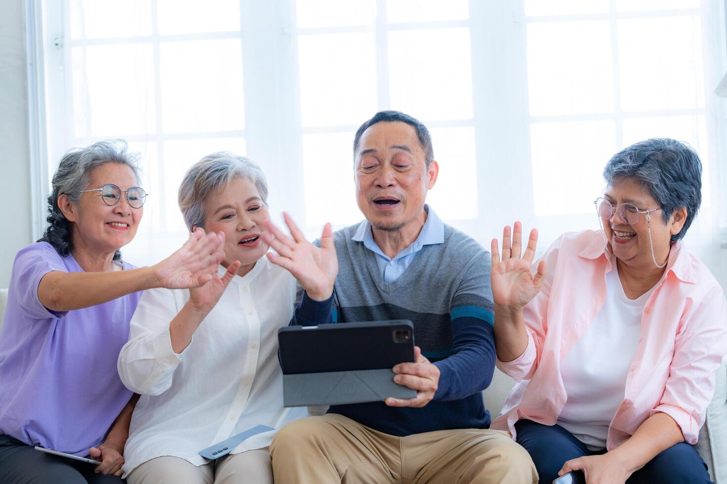 Happiness of the group females and male elderly talking with Call from smart tablet. Senior people are talking and enjoy together at the living room. Joyful retired friends enjoying relaxation. photo