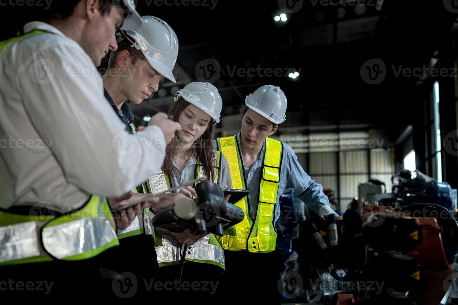 team engineers inspecting on machine with smart tablet. Worker works at heavy machine robot arm. The welding machine with a remote system in an industrial factory. Artificial intelligence concept. photo