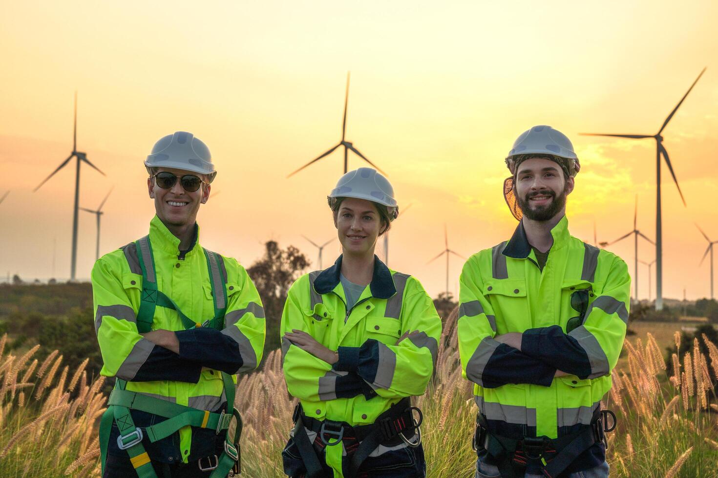Team Engineers men and woman checking and inspecting on construction with sunset sky. people operation. Wind turbine for electrical of clean energy and environment. Industrial of sustainable. photo