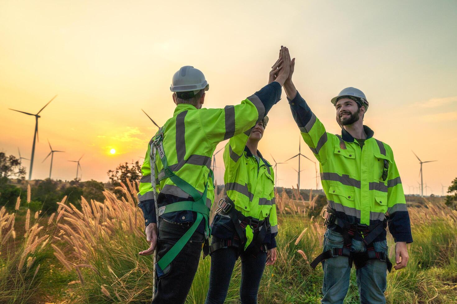 Team Engineers men and woman checking and inspecting on construction with sunset sky. people operation. Wind turbine for electrical of clean energy and environment. Industrial of sustainable. photo