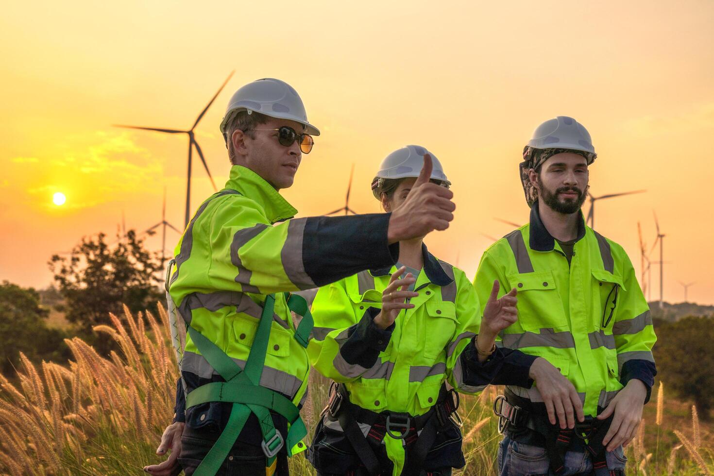 Team Engineers men and woman checking and inspecting on construction with sunset sky. people operation. Wind turbine for electrical of clean energy and environment. Industrial of sustainable. photo