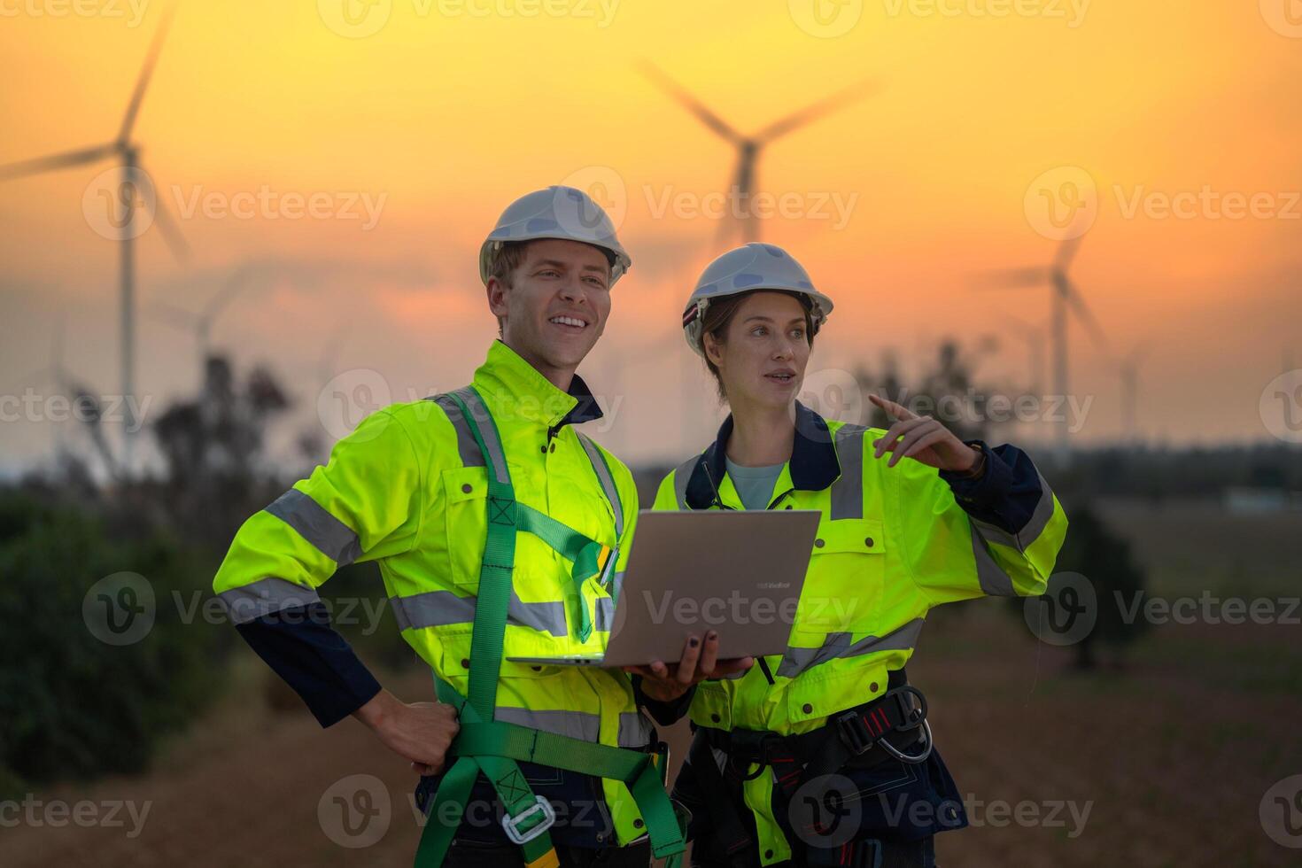 Engineers man and woman inspecting construction of WIND TURBINE FARM. WIND TURBINE with an energy storage system operated by Super Energy Corporation. Workers Meeting to check AROUND THE AREA. photo