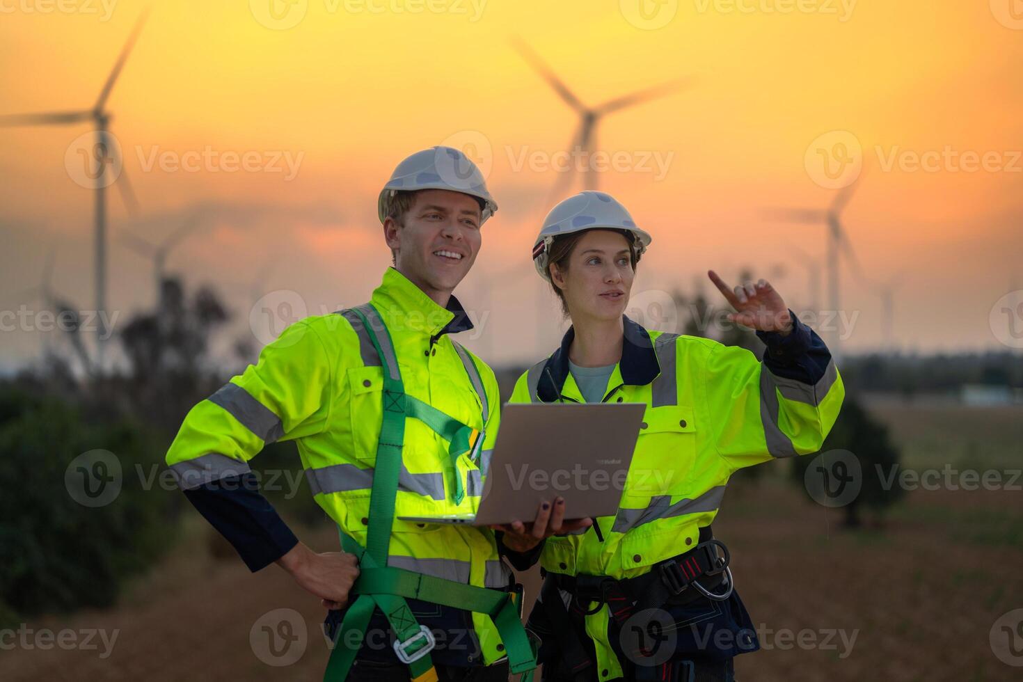 Engineers man and woman inspecting construction of WIND TURBINE FARM. WIND TURBINE with an energy storage system operated by Super Energy Corporation. Workers Meeting to check AROUND THE AREA. photo