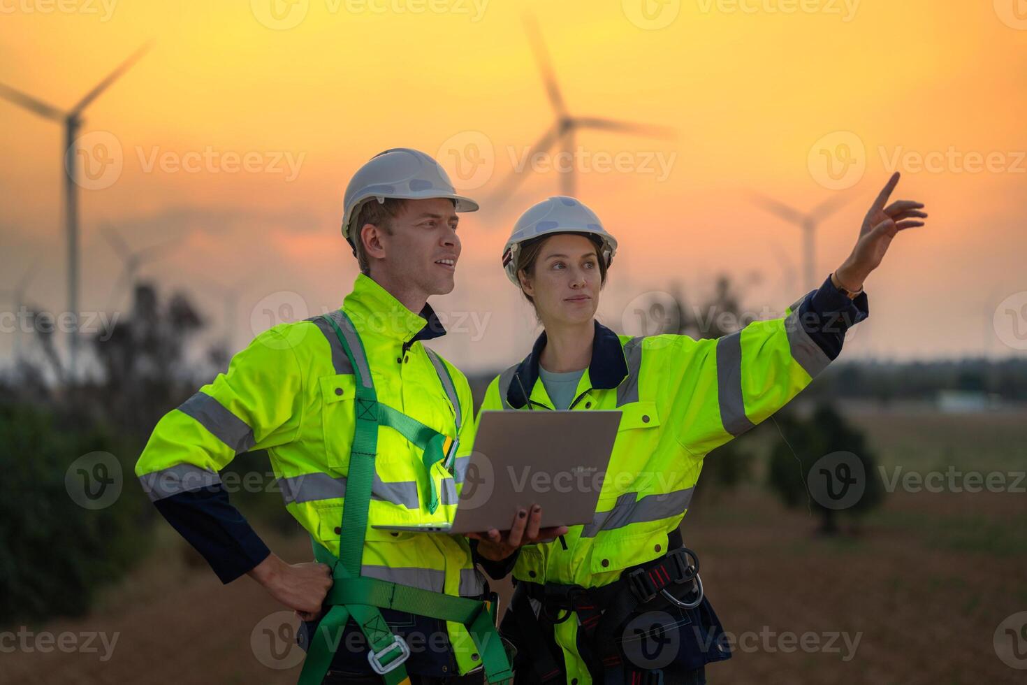 Team Engineers men and woman checking and inspecting on construction with sunset sky. people operation. Wind turbine for electrical of clean energy and environment. Industrial of sustainable. photo