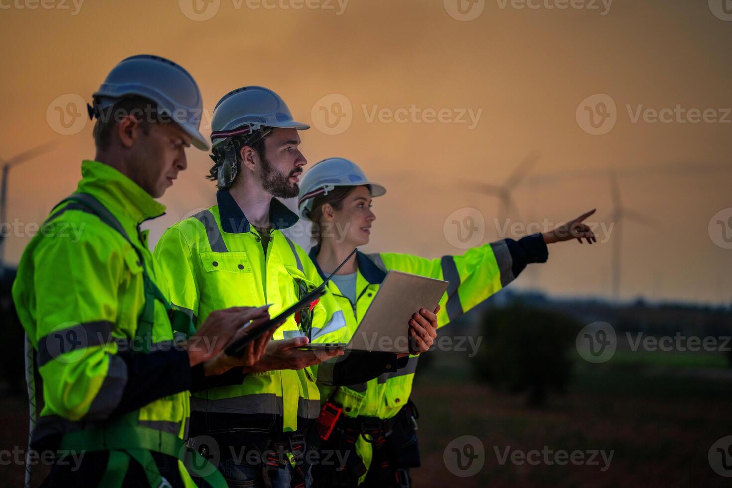 Team Engineers men and woman checking and inspecting on construction with sunset sky. people operation. Wind turbine for electrical of clean energy and environment. Industrial of sustainable. photo