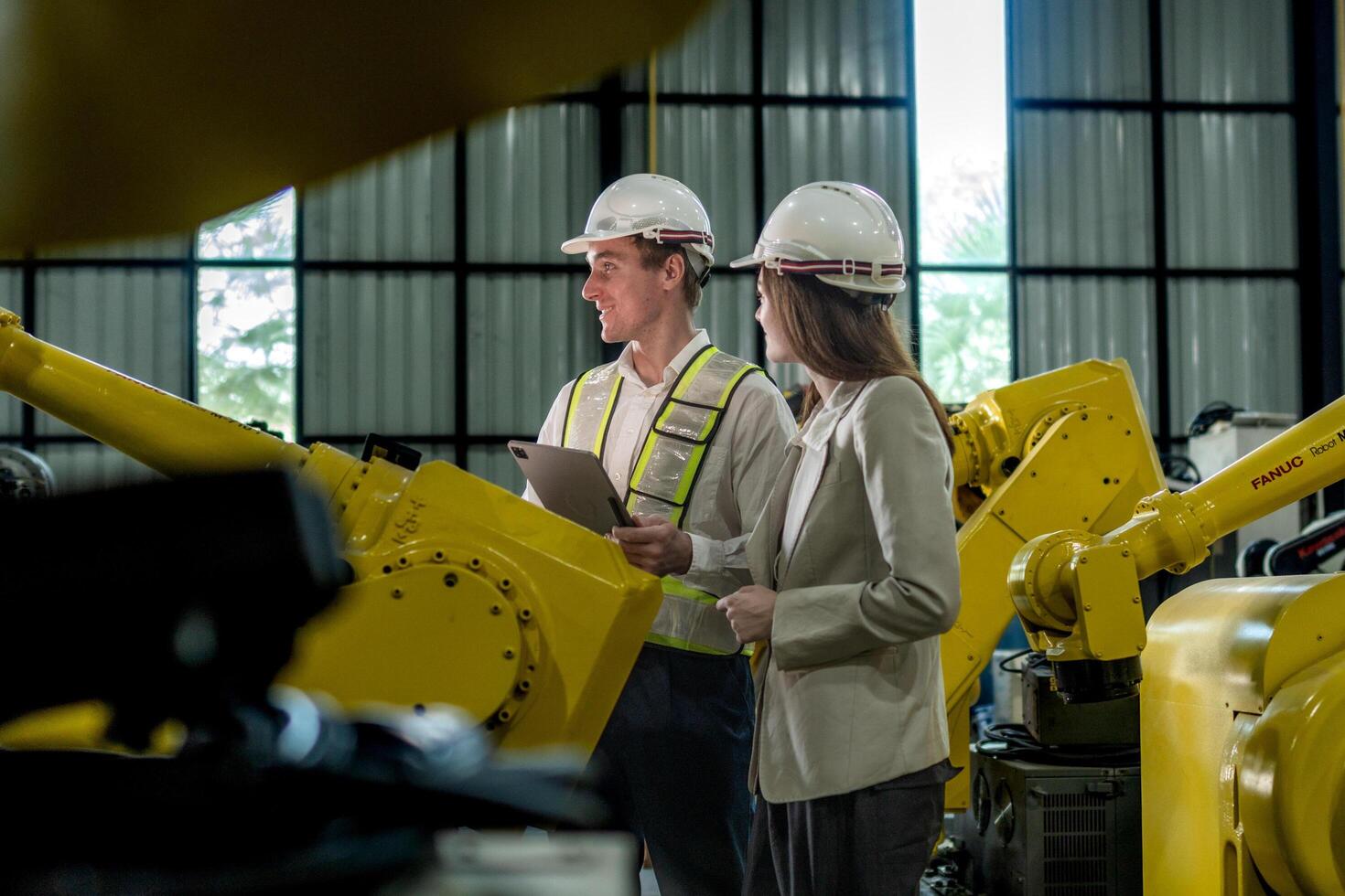 team engineers inspecting on machine with smart tablet. Worker works at heavy machine robot arm. The welding machine with a remote system in an industrial factory. Artificial intelligence concept. photo