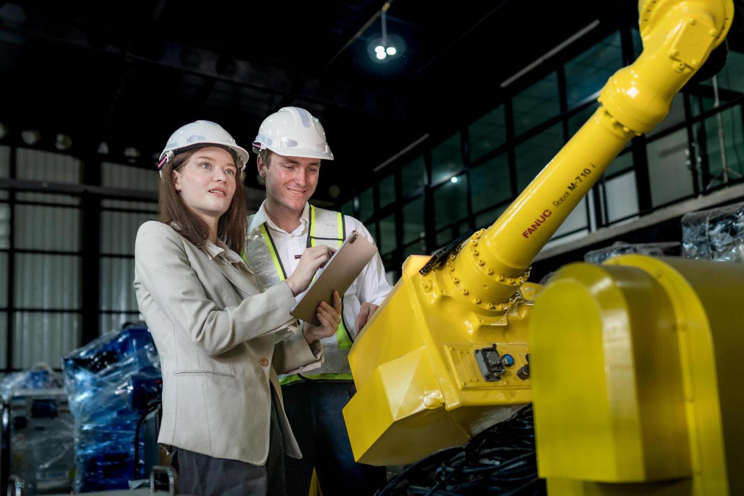 team engineers inspecting on machine with smart tablet. Worker works at heavy machine robot arm. The welding machine with a remote system in an industrial factory. Artificial intelligence concept. photo