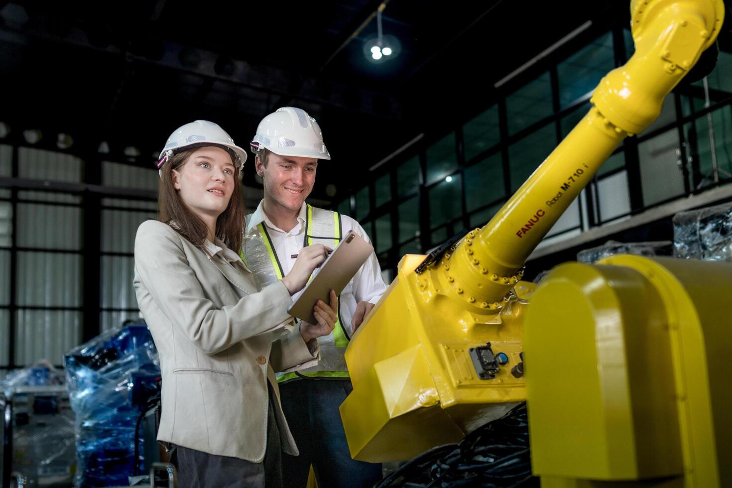 team engineers inspecting on machine with smart tablet. Worker works at heavy machine robot arm. The welding machine with a remote system in an industrial factory. Artificial intelligence concept. photo