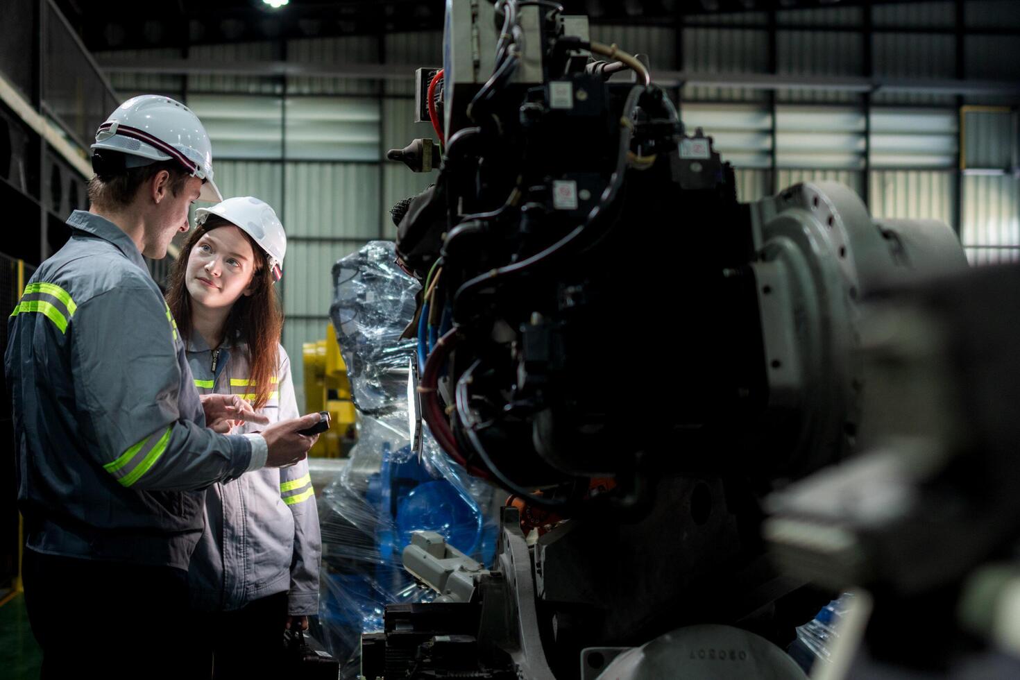 team engineers inspecting on machine with smart tablet. Worker works at heavy machine robot arm. The welding machine with a remote system in an industrial factory. Artificial intelligence concept. photo