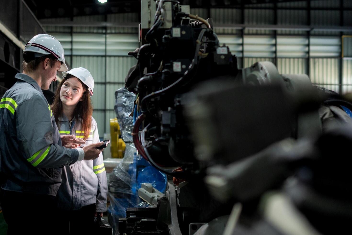team engineers inspecting on machine with smart tablet. Worker works at heavy machine robot arm. The welding machine with a remote system in an industrial factory. Artificial intelligence concept. photo