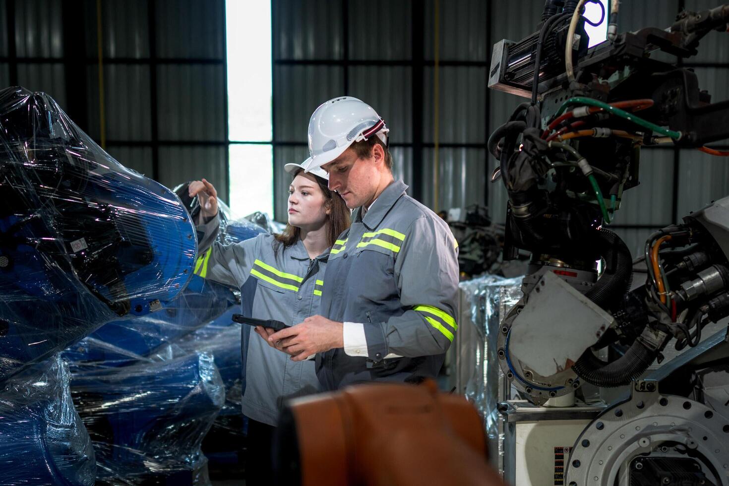 team engineers inspecting on machine with smart tablet. Worker works at heavy machine robot arm. The welding machine with a remote system in an industrial factory. Artificial intelligence concept. photo