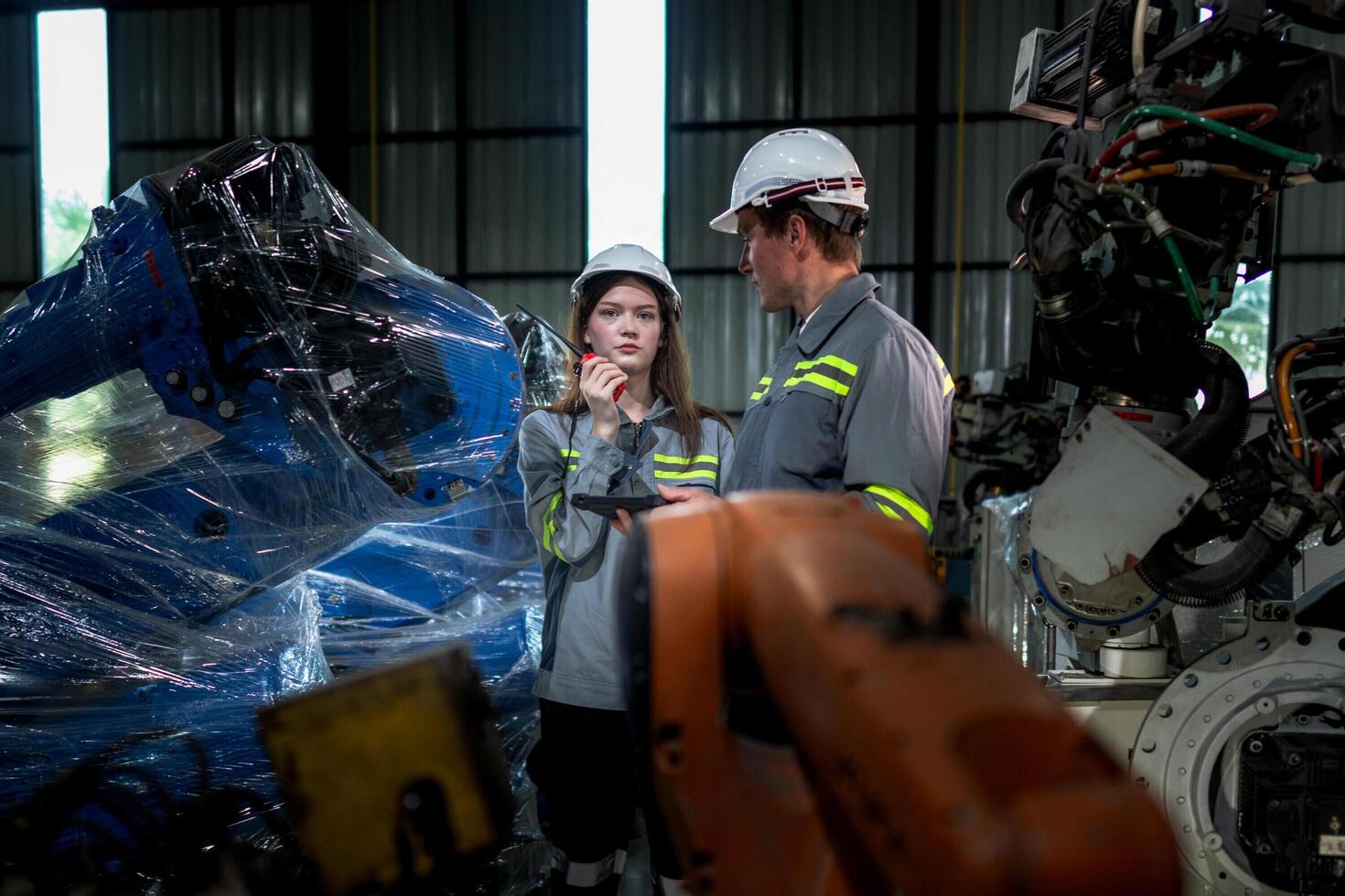 team engineers inspecting on machine with smart tablet. Worker works at heavy machine robot arm. The welding machine with a remote system in an industrial factory. Artificial intelligence concept. photo