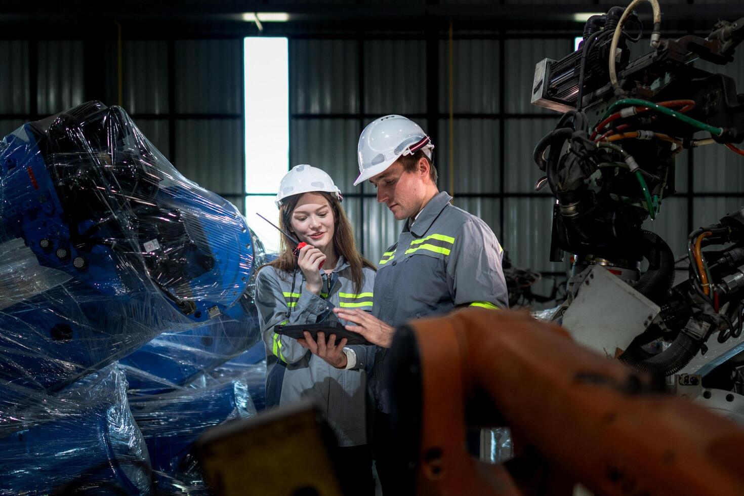 team engineers inspecting on machine with smart tablet. Worker works at heavy machine robot arm. The welding machine with a remote system in an industrial factory. Artificial intelligence concept. photo