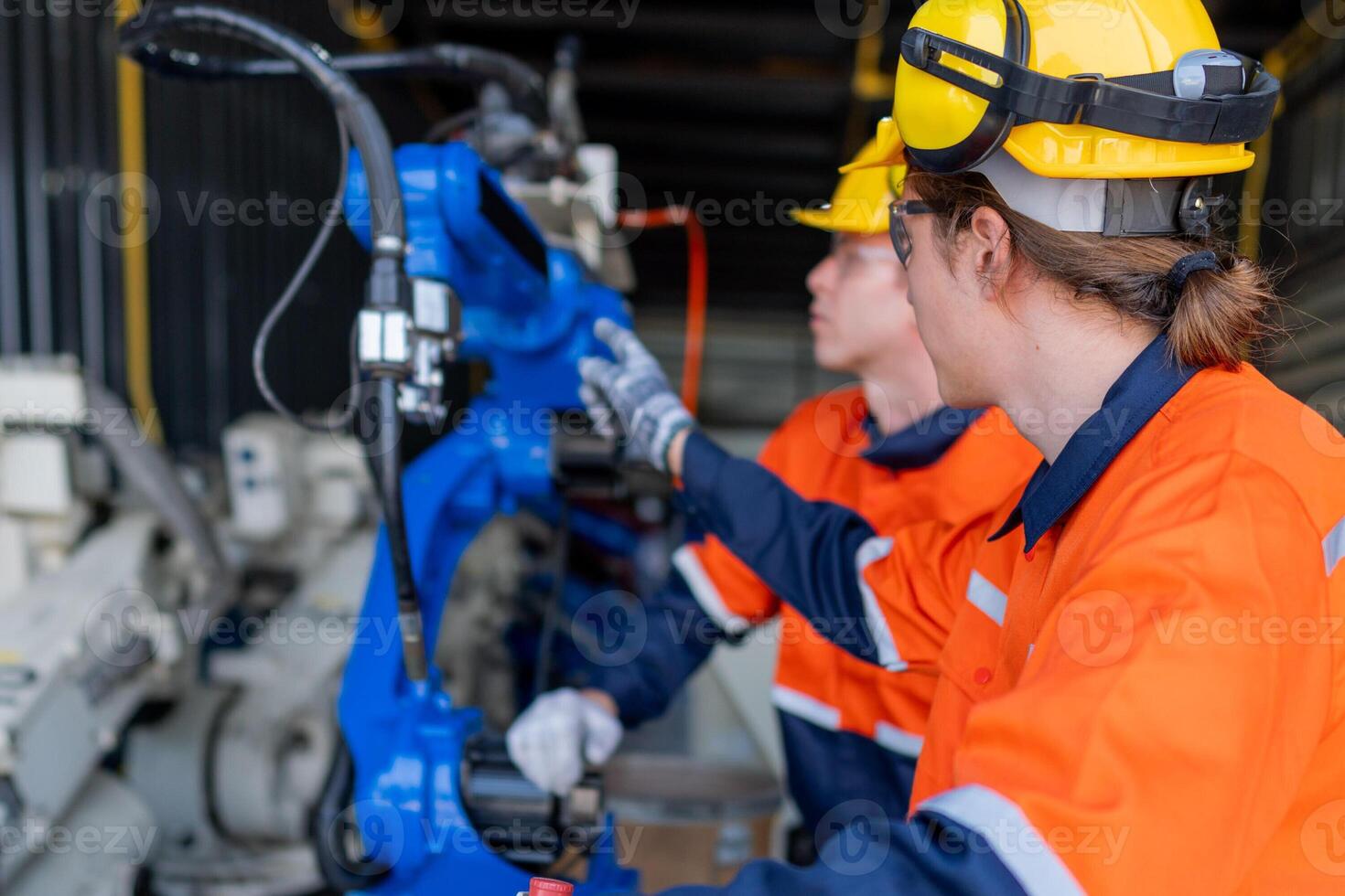 group of male engineer workers maintenance automatic robotic arm machine in a dark room factory. worker checking and repairing automatic robot hand machine. Worker wearing safety glasses and helmet. photo