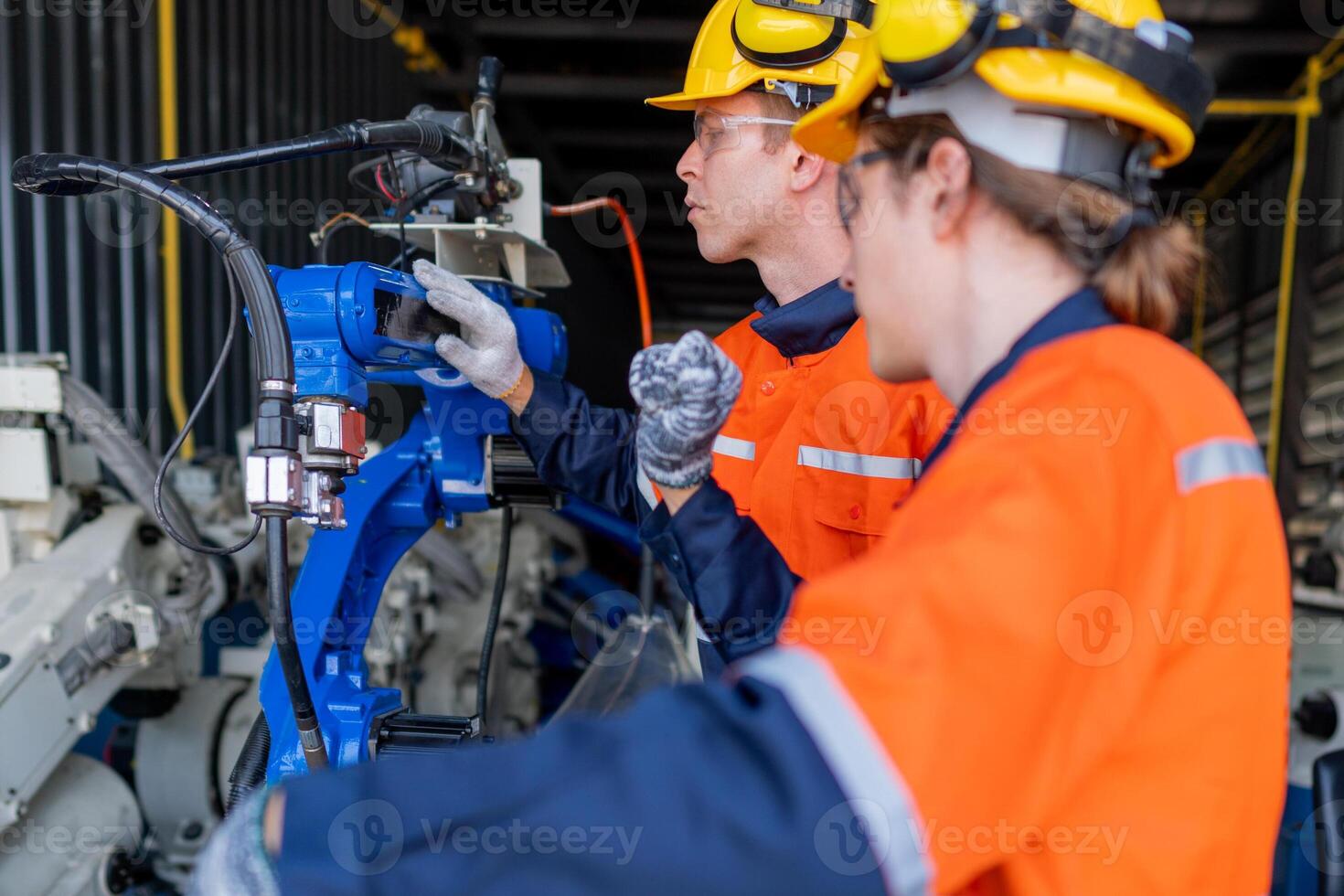 group of male engineer workers maintenance automatic robotic arm machine in a dark room factory. worker checking and repairing automatic robot hand machine. Worker wearing safety glasses and helmet. photo