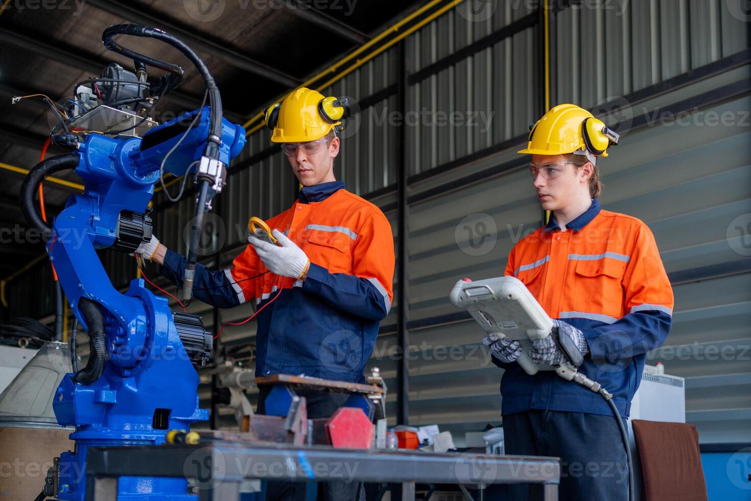 group of male engineer workers maintenance automatic robotic arm machine in a dark room factory. worker checking and repairing automatic robot hand machine. Worker wearing safety glasses and helmet. photo