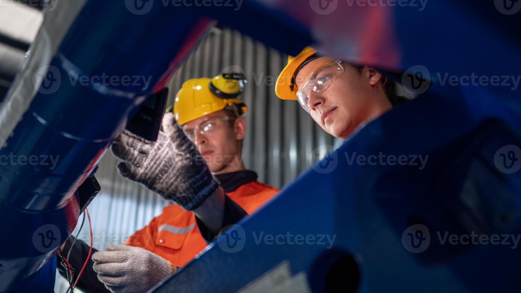 group of male engineer workers maintenance automatic robotic arm machine in a dark room factory. worker checking and repairing automatic robot hand machine. Worker wearing safety glasses and helmet. photo
