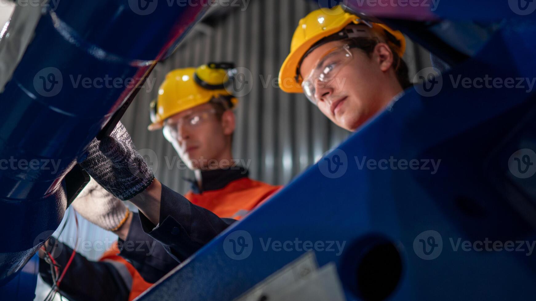 group of male engineer workers maintenance automatic robotic arm machine in a dark room factory. worker checking and repairing automatic robot hand machine. Worker wearing safety glasses and helmet. photo