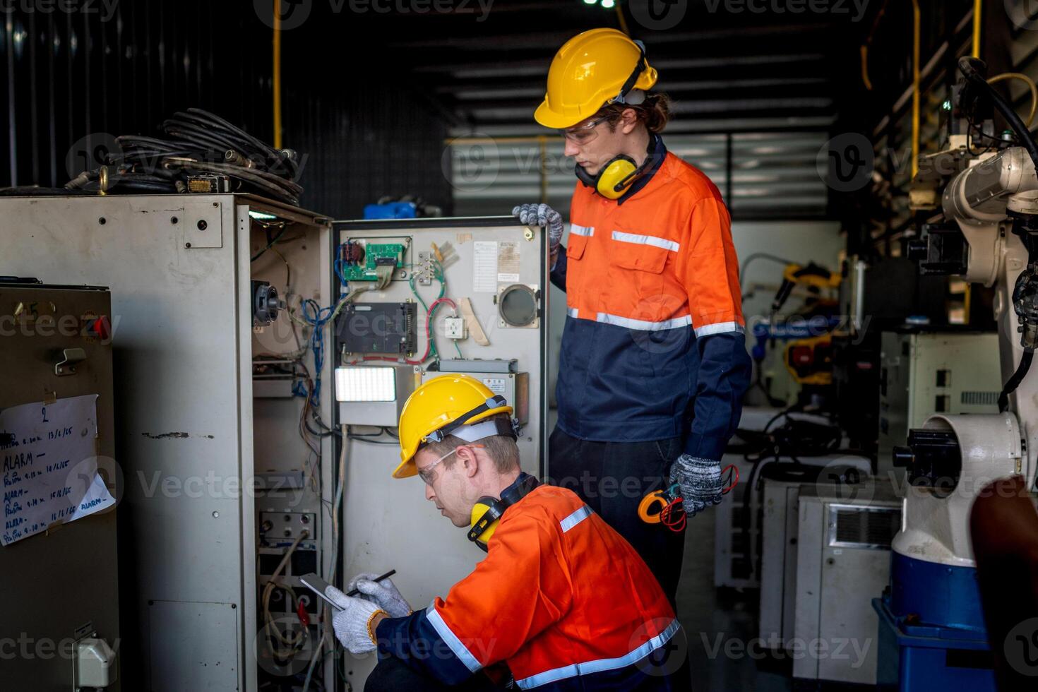 group of male engineer workers maintenance automatic robotic arm machine in a dark room factory. worker checking and repairing automatic robot hand machine. Worker wearing safety glasses and helmet. photo