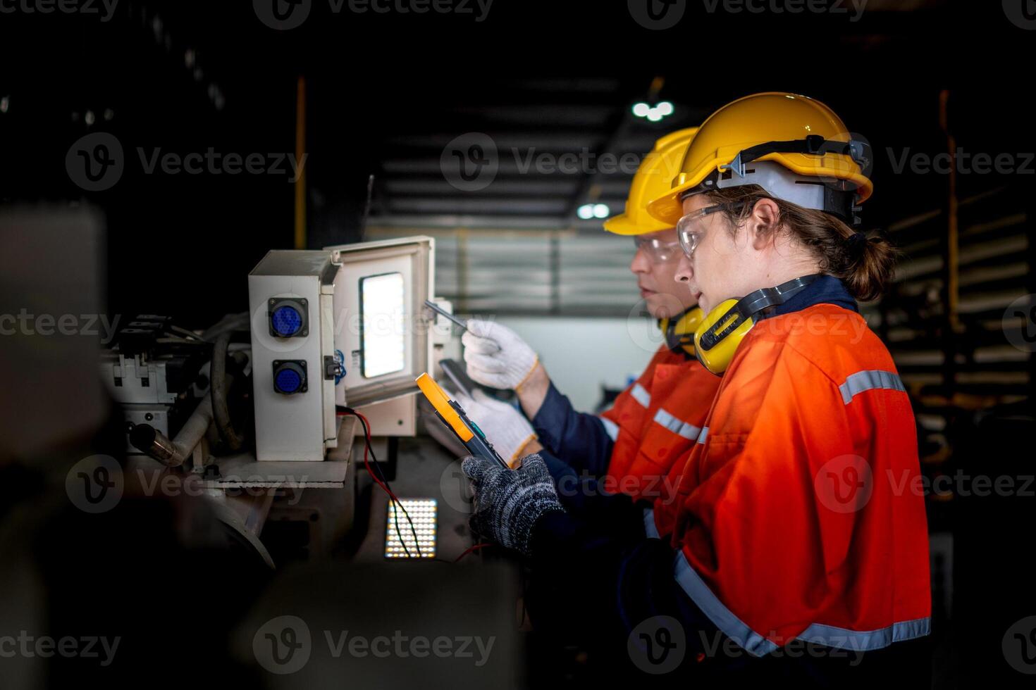 group of male engineer workers maintenance automatic robotic arm machine in a dark room factory. worker checking and repairing automatic robot hand machine. Worker wearing safety glasses and helmet. photo