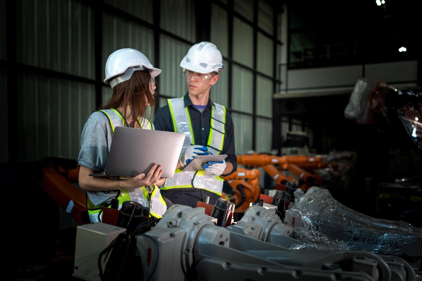 team engineers inspecting on machine with smart tablet. Worker works at heavy machine robot arm. The welding machine with a remote system in an industrial factory. Artificial intelligence concept. photo