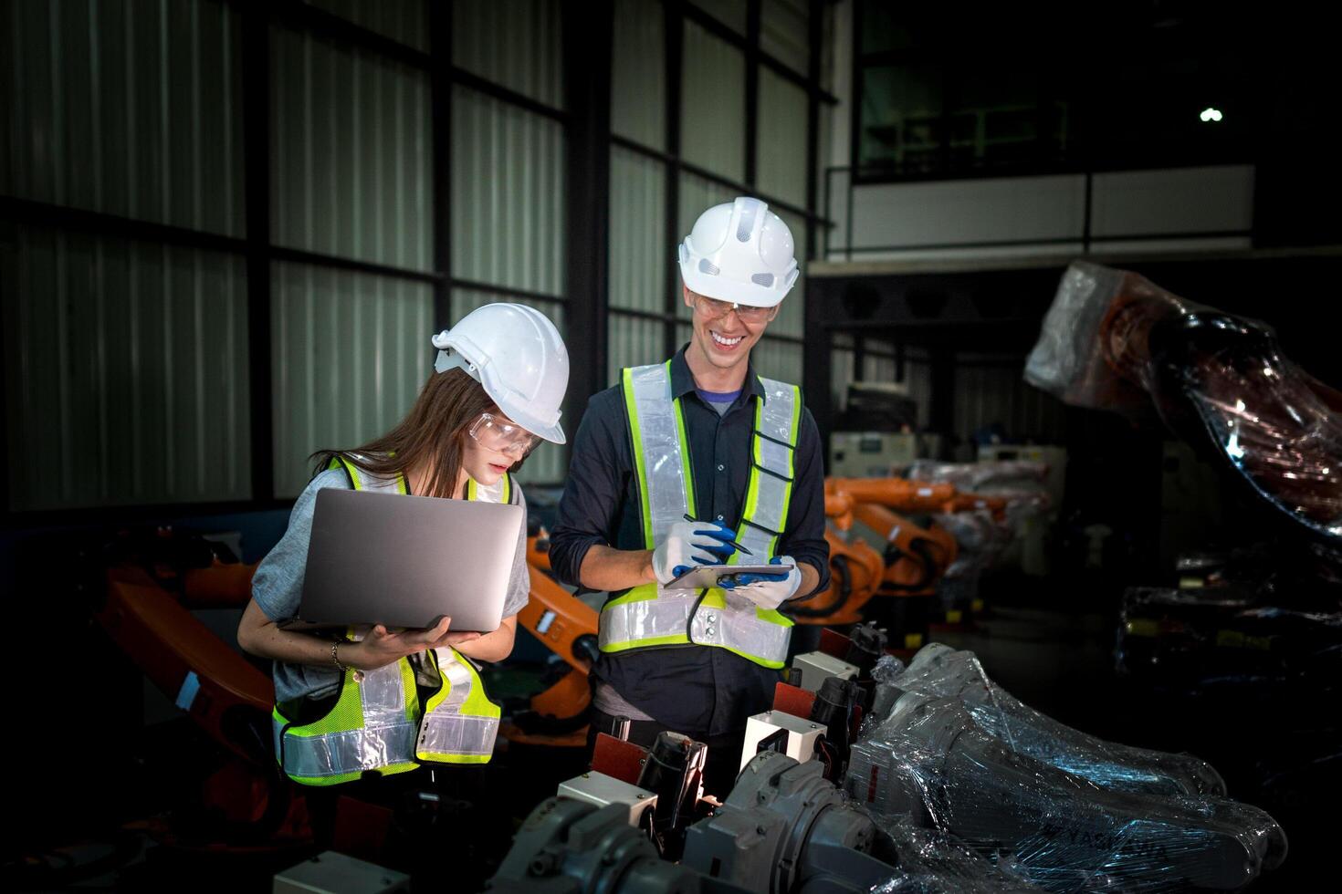 team engineers inspecting on machine with smart tablet. Worker works at heavy machine robot arm. The welding machine with a remote system in an industrial factory. Artificial intelligence concept. photo