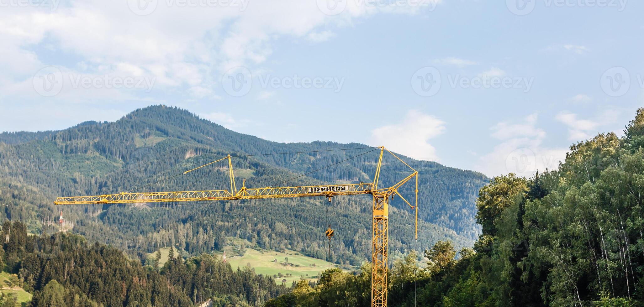 large tower crane works at a construction site in the mountains, mountains Alps background photo