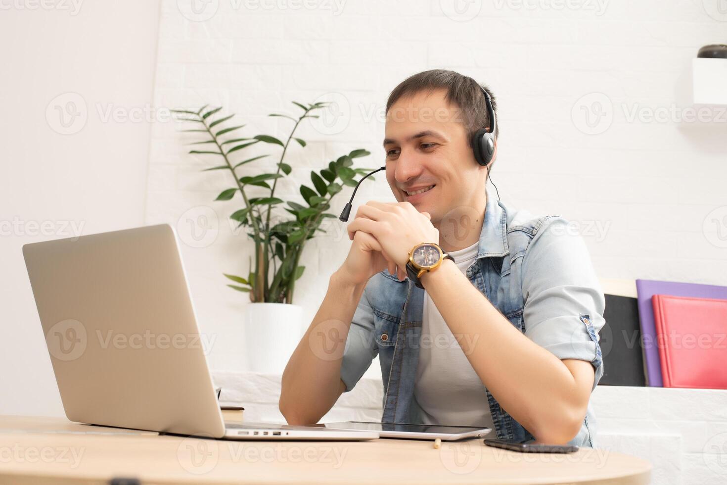 Happy young man smiling, as he works on his laptop to get all his business done early in the morning photo