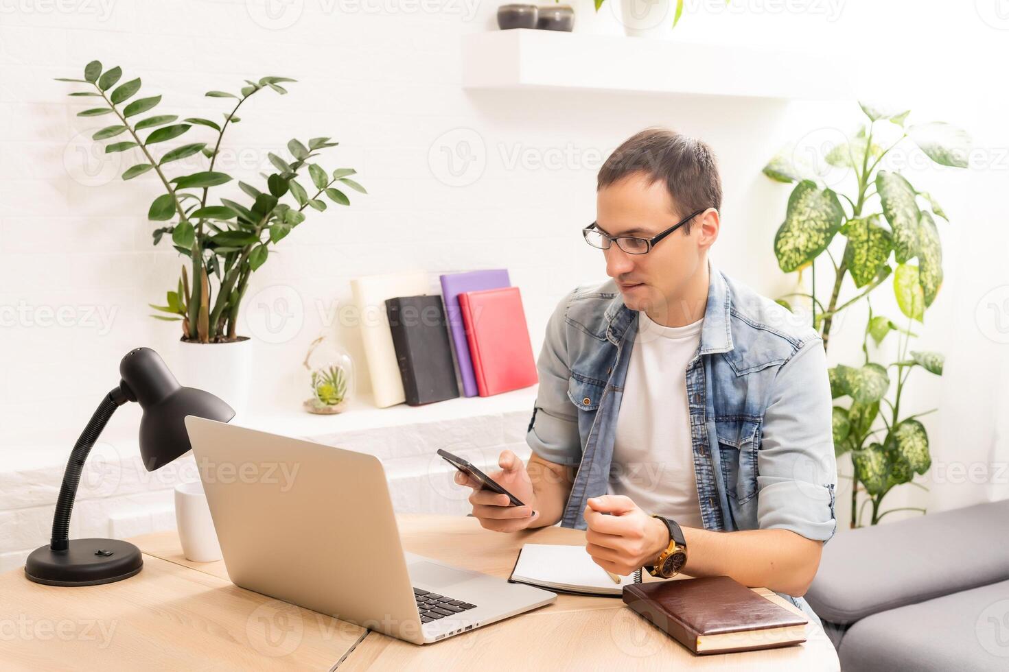 Smiling young man working on laptop, checking email in morning, writing message in social network, happy young male using internet banking service, searching information photo