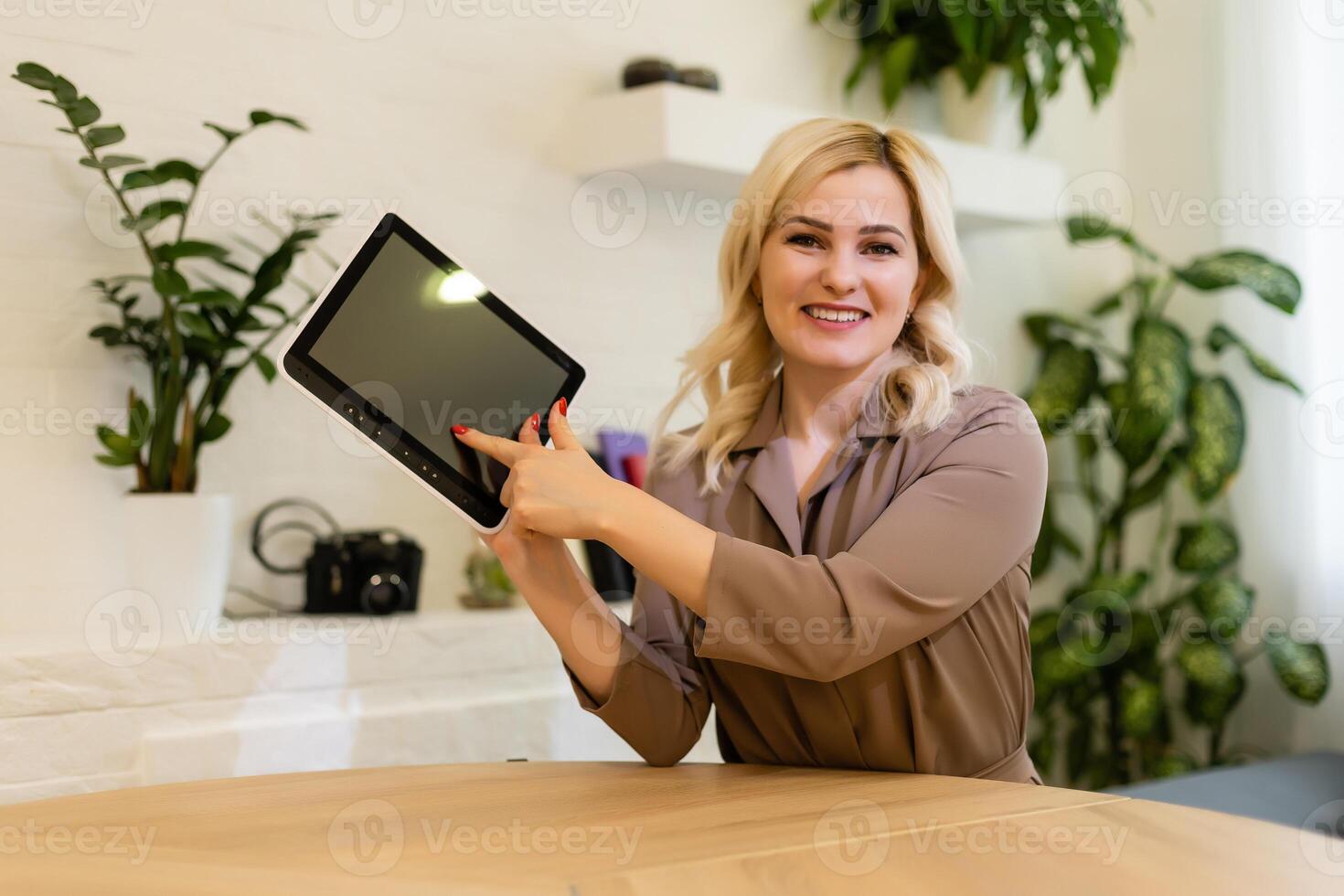 Woman displaying her tablet computer with the blank black screen turned to face the camera for your text or advertisement photo