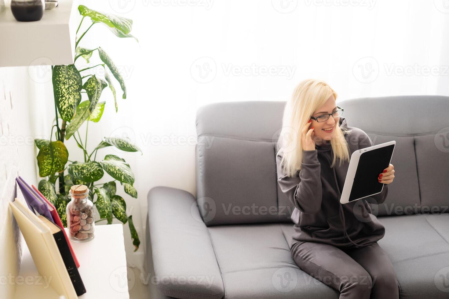 Beautiful young woman in casual clothes is using a digital tablet and smiling at home photo
