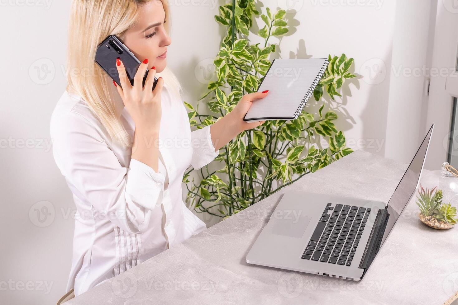Portrait of a smiling young woman using laptop and smartphone photo