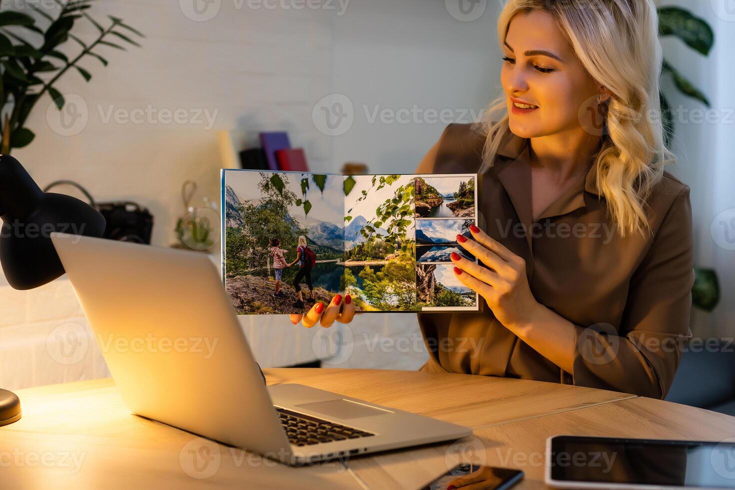 woman holding and presenting photobook near laptop photo