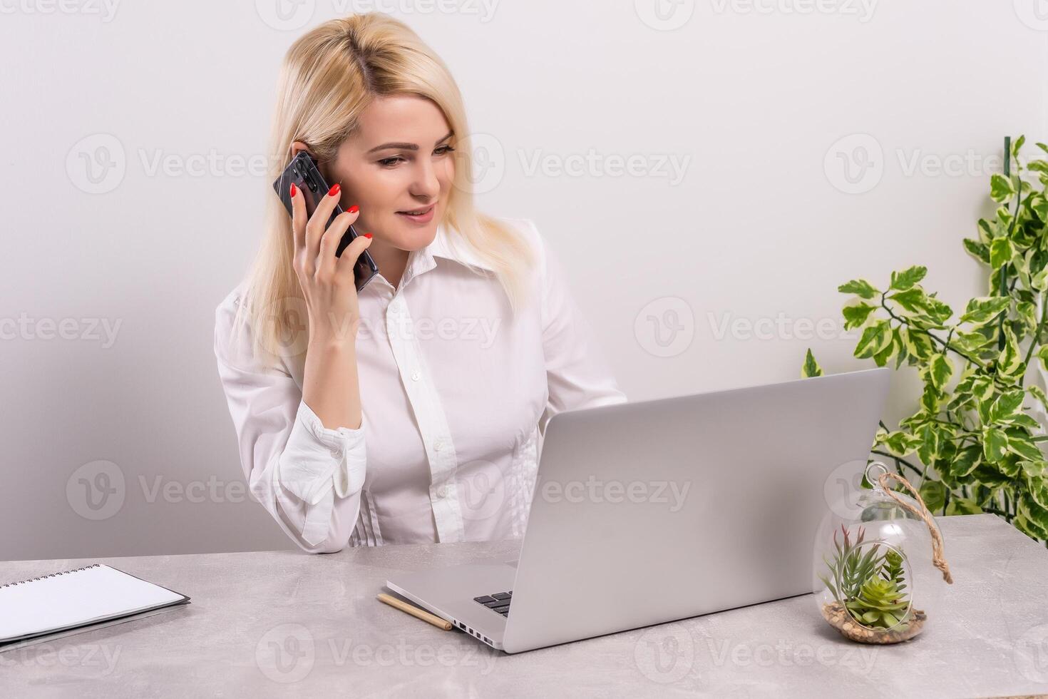 Portrait of a smiling young woman using laptop and smartphone photo