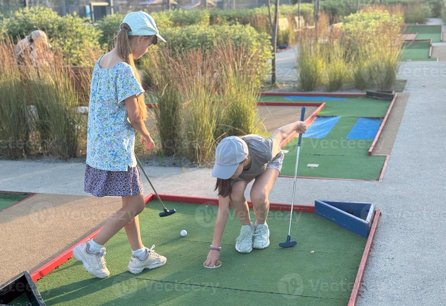 teenage girls playing mini golf in summer photo