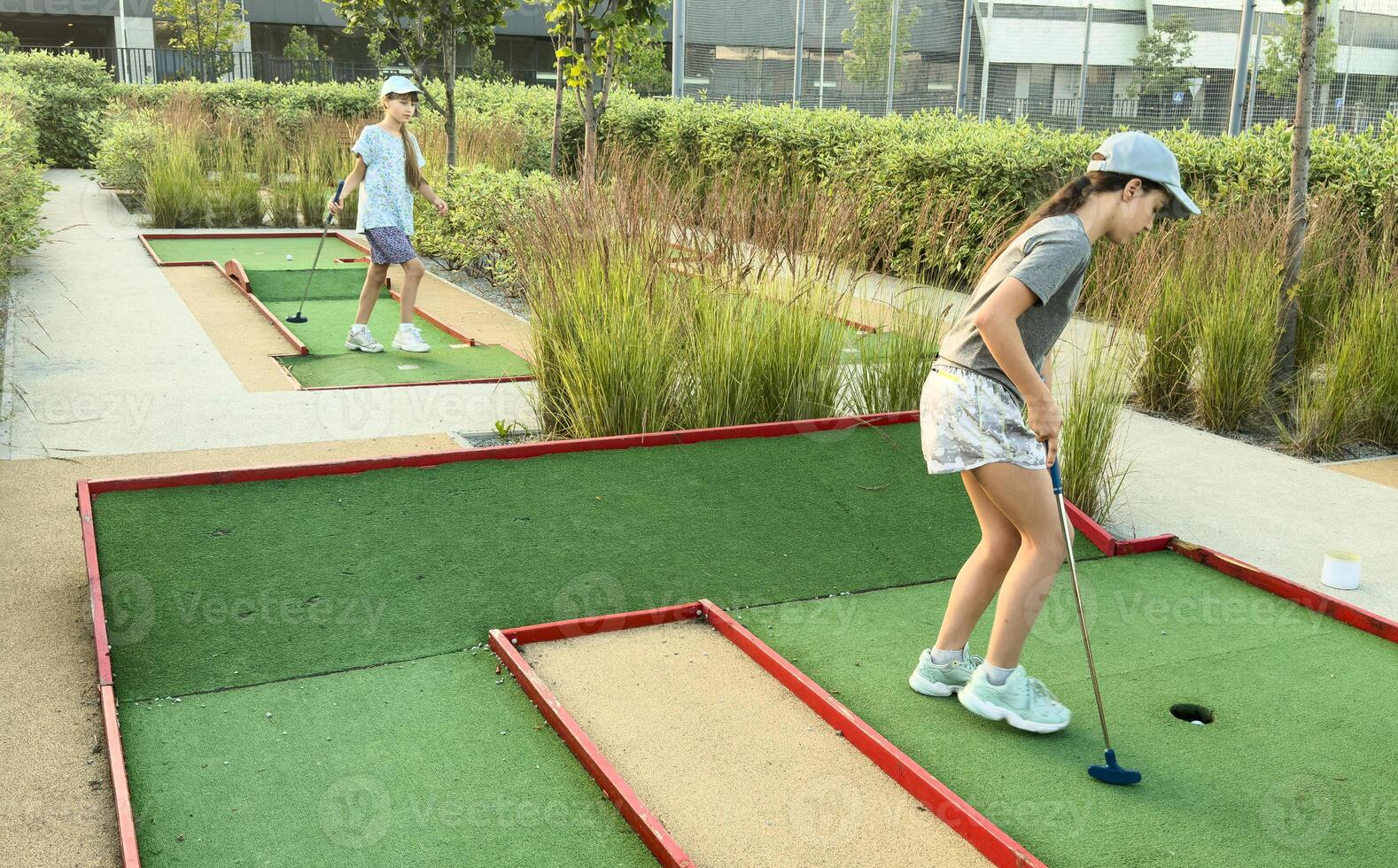teenage girls play mini golf on the course. photo