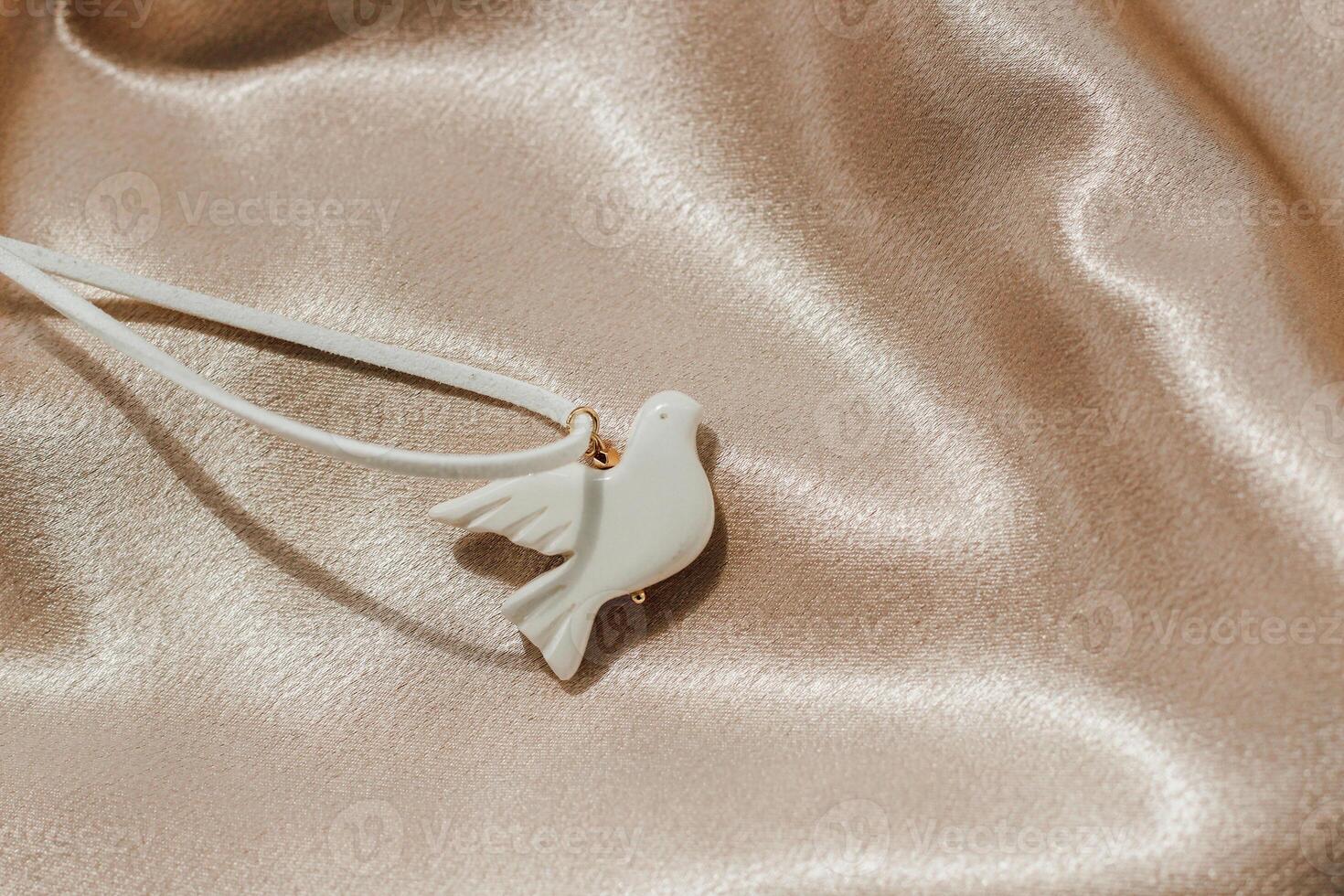 bijouterie white bird made of polymer clay on the background of silk shiny fabric photo