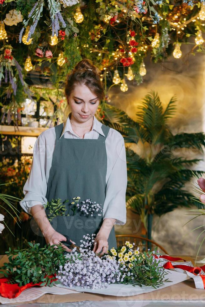 A woman in her florist shop collects bouquets of flowers. The concept of a small business. Bouquets of tulips for the holiday on March 8. photo