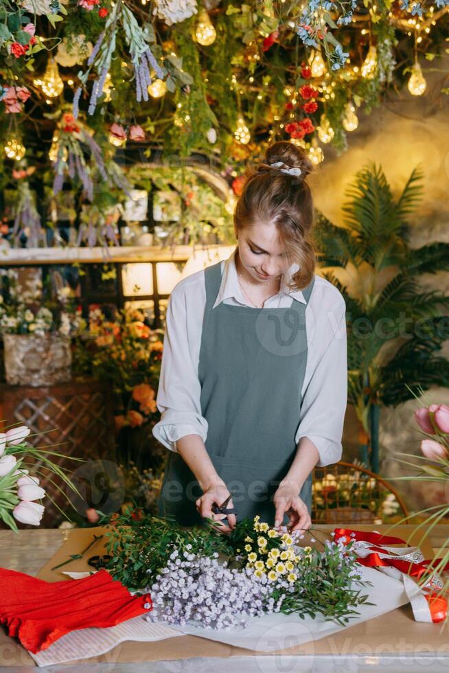 A woman in her florist shop collects bouquets of flowers. The concept of a small business. Bouquets of tulips for the holiday on March 8. photo