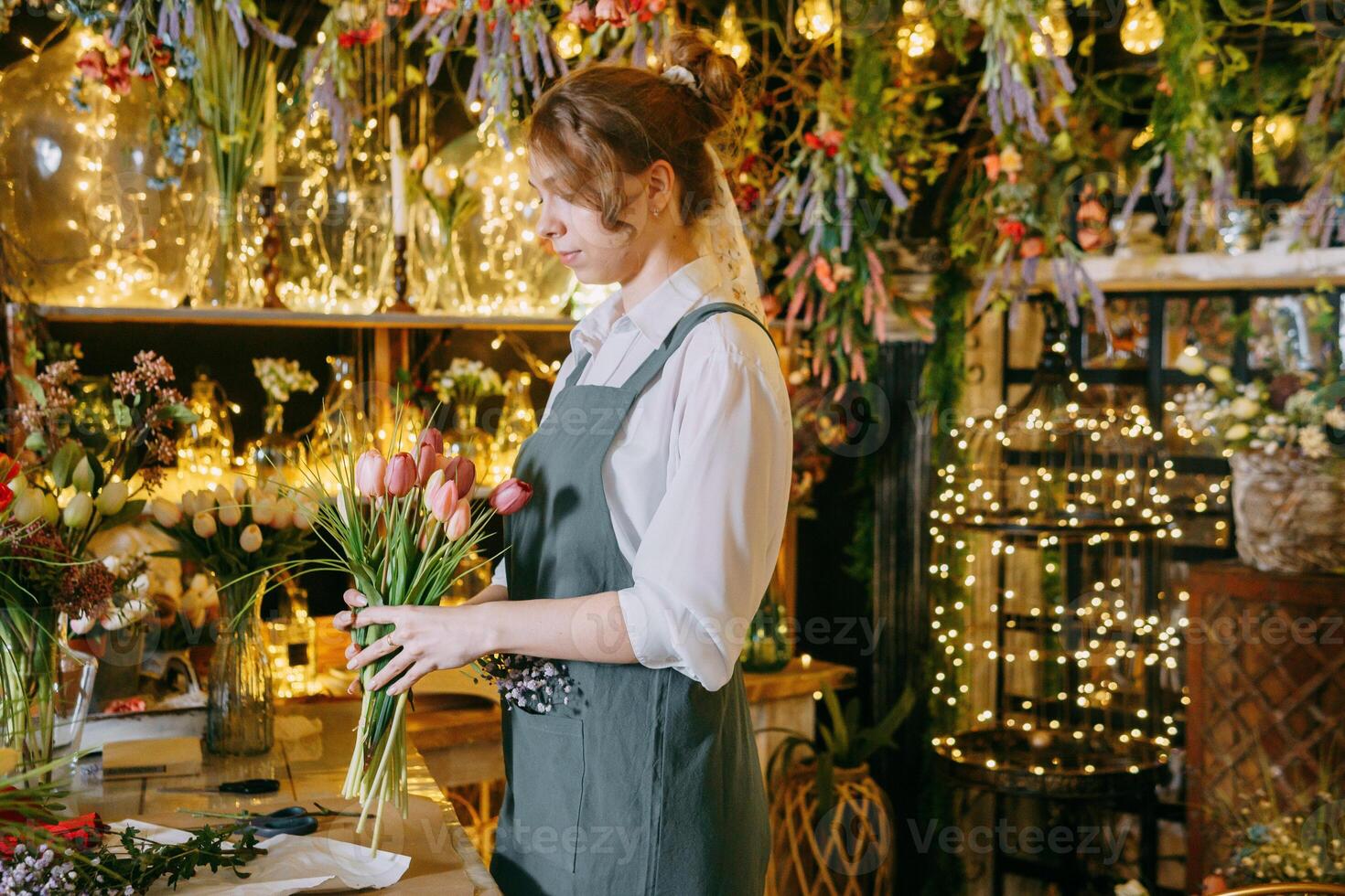 A woman in her florist shop collects bouquets of flowers. The concept of a small business. Bouquets of tulips for the holiday on March 8. photo