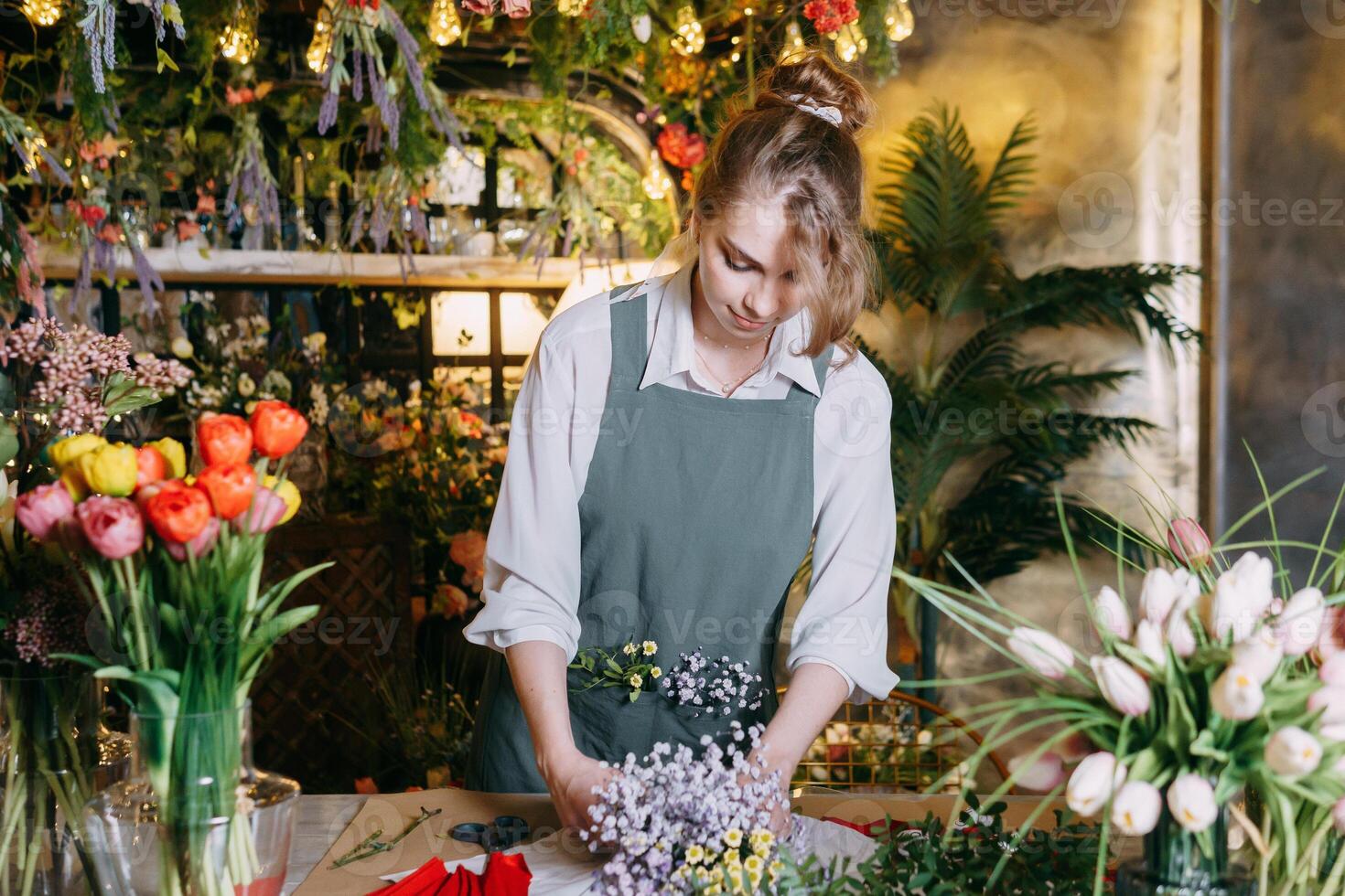 A woman in her florist shop collects bouquets of flowers. The concept of a small business. Bouquets of tulips for the holiday on March 8. photo