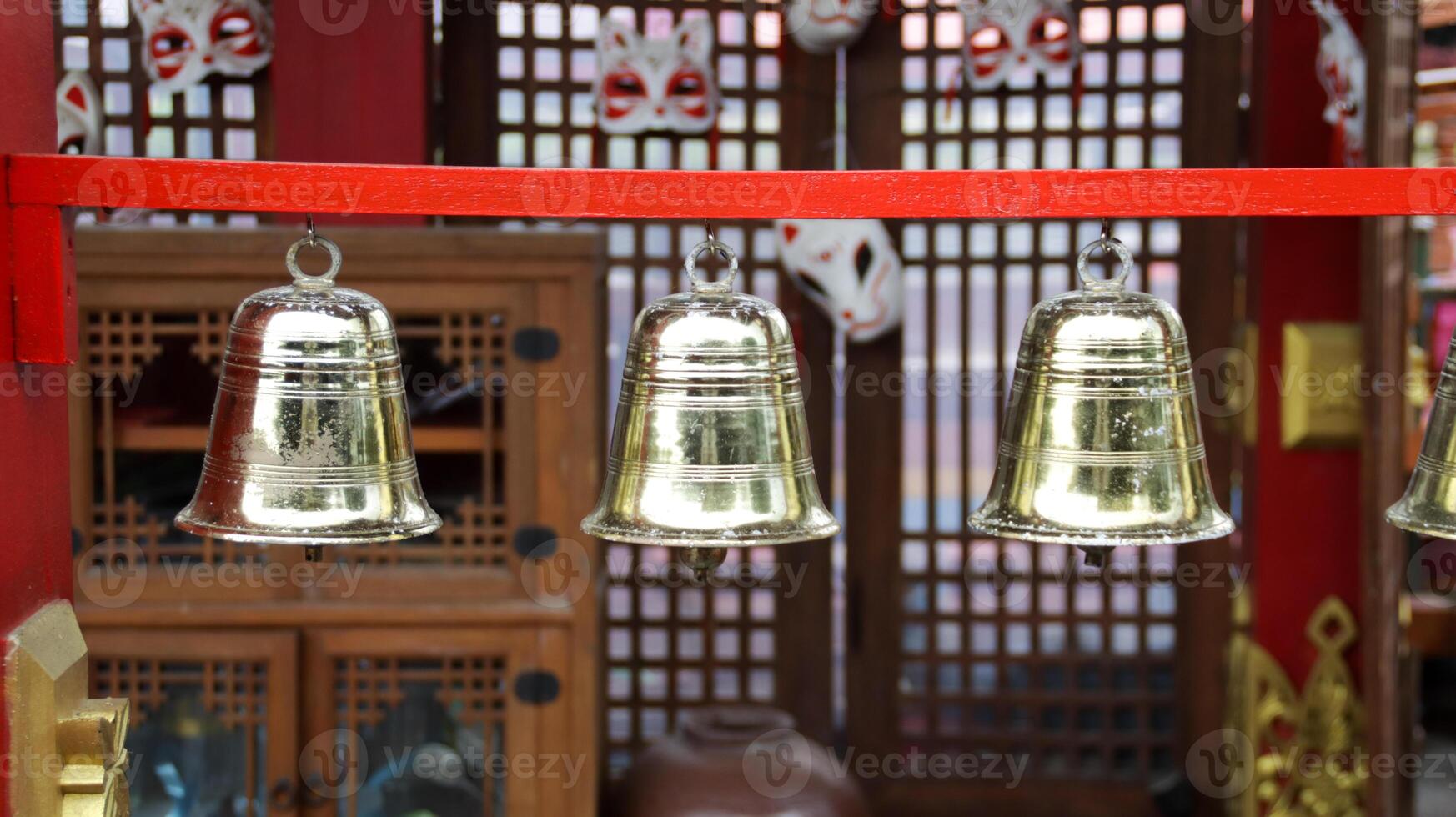 Golden Bells Hanging on Red Frame with Wooden Background in Traditional Setting photo