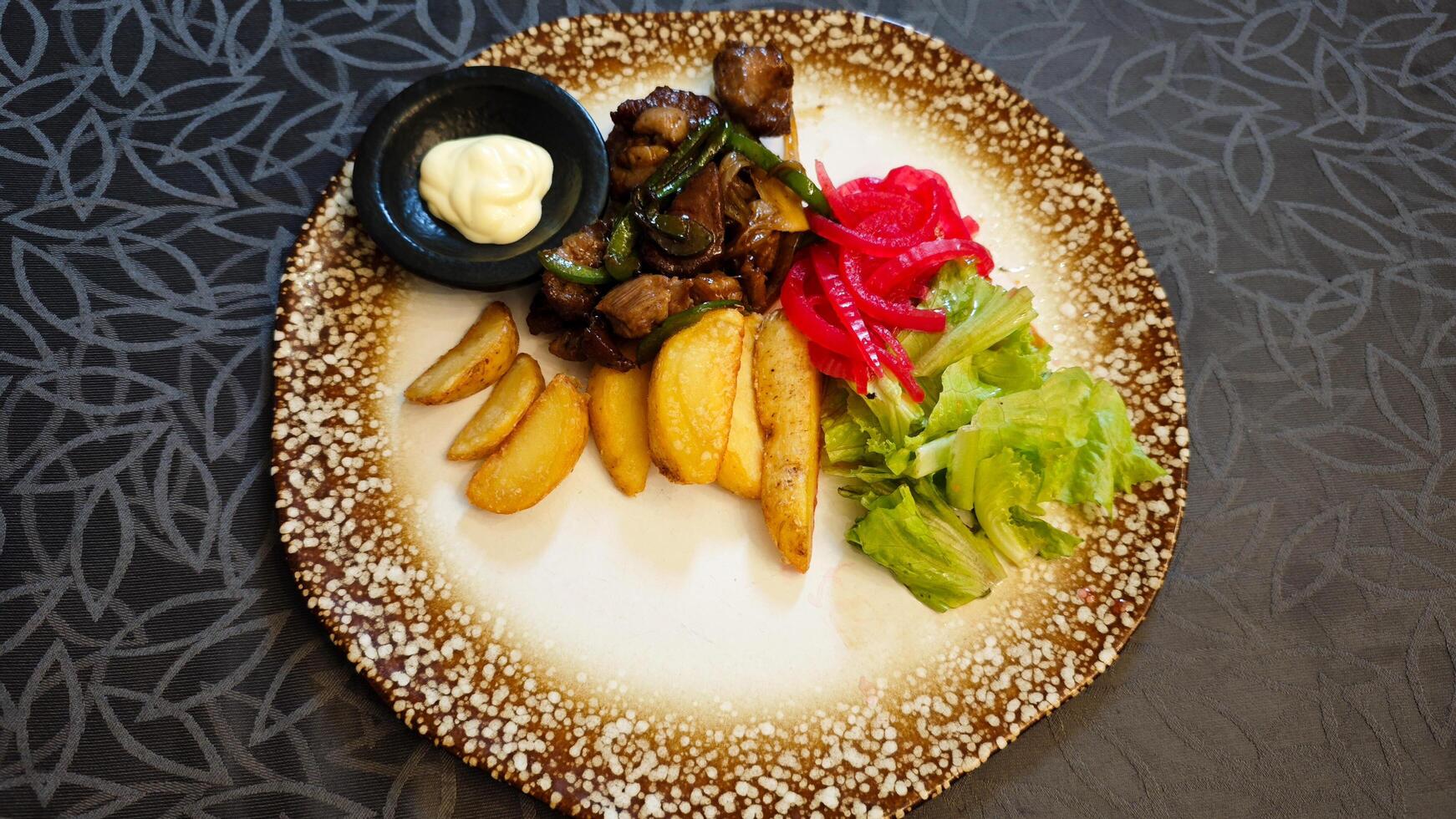 Saikoro Mongolian Beef with Wedge Potatoes and Pickled Vegetables on a Rustic Plate in an Elegant Restaurant Setting photo