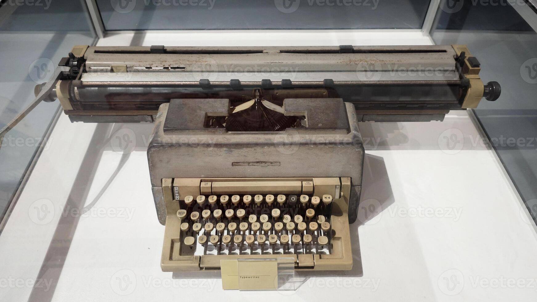 Vintage Retro Typewriter with Beige Keys and Metal Frame on Display in Glass Case at Museum Exhibit photo