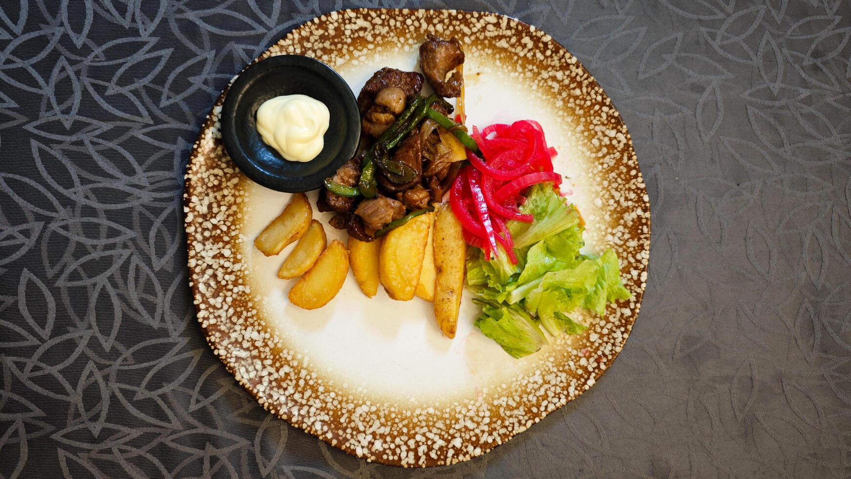 Saikoro Mongolian Beef with Wedge Potatoes and Pickled Vegetables on a Rustic Plate in an Elegant Restaurant Setting photo