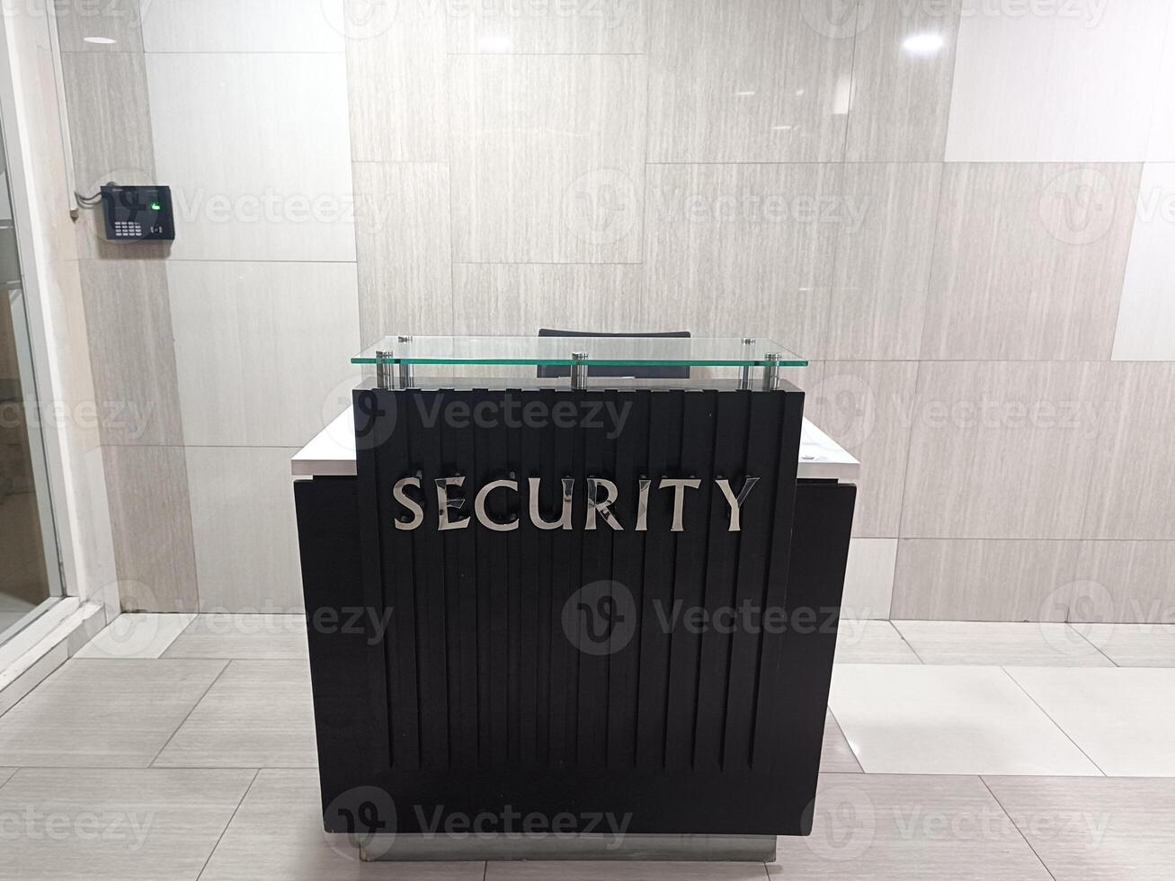 Modern Security Station with Black Desk and Silver Lettering in a Clean Office Building with Tiled Walls and Floor photo