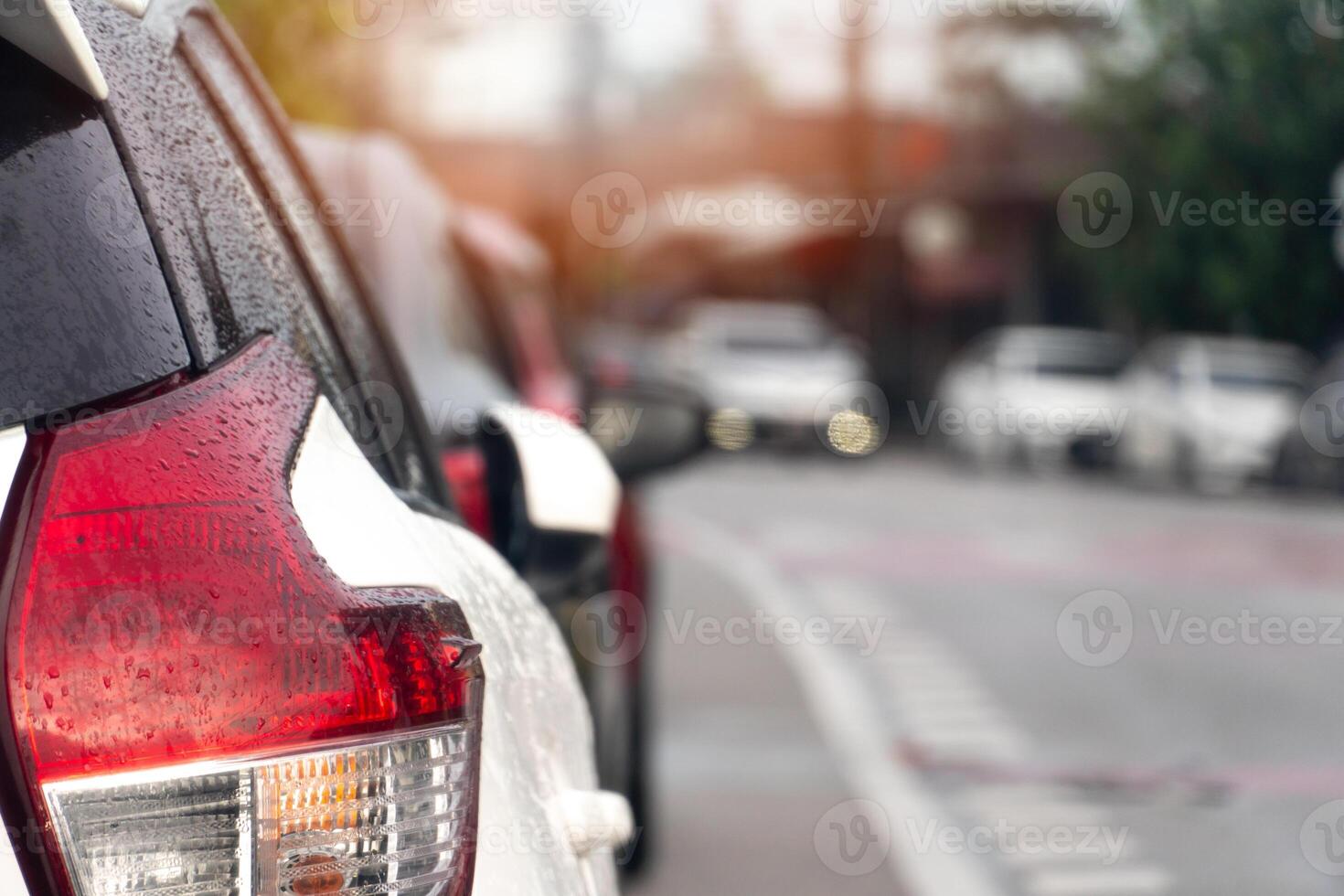 Luxury of white car stop on the asphalt road. On the car with drop of weter rain. Traveling in the provinces during the bright period. Many cars are parked in a queue on the side of the road. photo
