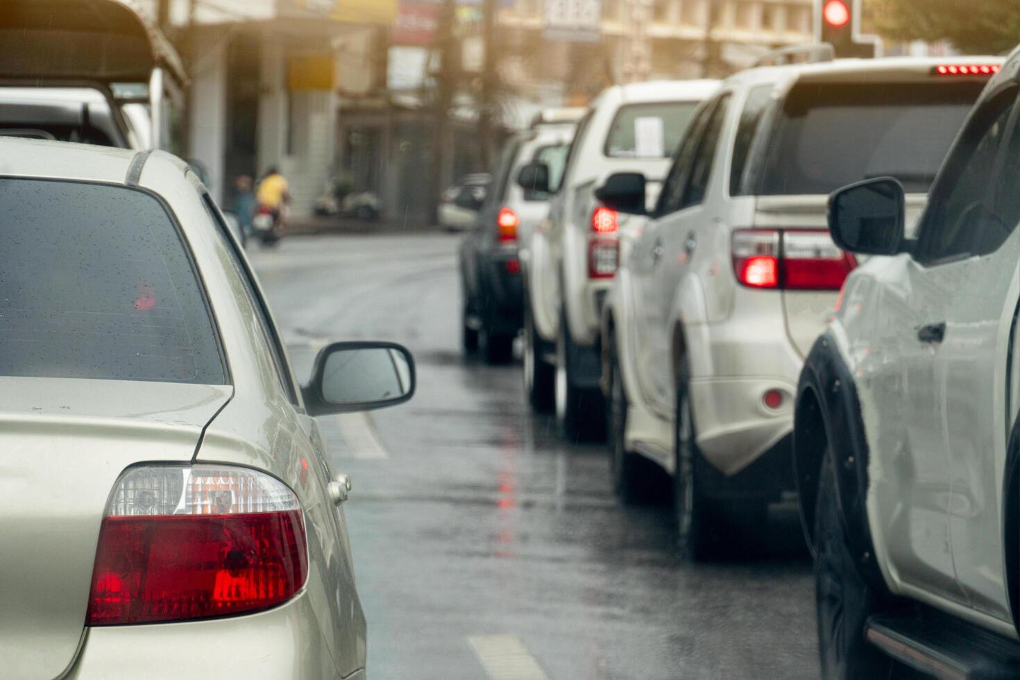 Rear side of car on wet asphalt road. Cars were waiting for the traffic lights at the intersection. Background blurred of town. photo
