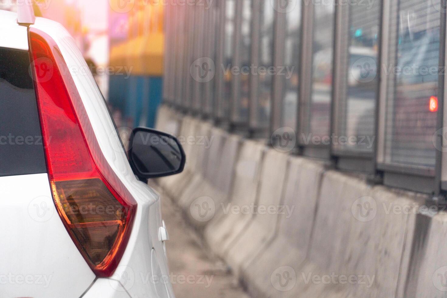 Rear side of white car close up of long tail light. Driving on tha road beside with barrier of concrete and sound protection at day in Thailand. photo